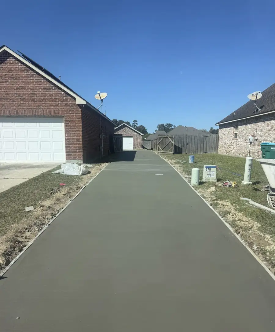 Freshly poured concrete driveway running between two brick homes