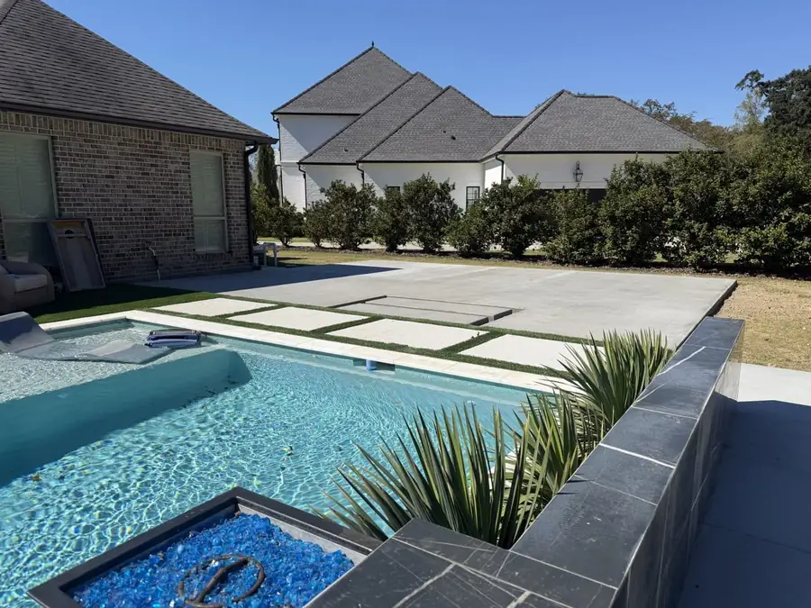 Broom-finish concrete pad with steps behind a pool and stepping pads